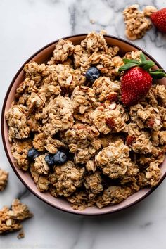 a bowl filled with granola and blueberries on top of a marble countertop