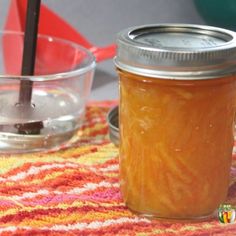 a glass jar filled with liquid sitting on top of a colorful table cloth next to a bowl