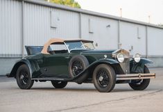 an old green car parked in front of a building