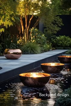 some bowls are sitting in the middle of a water feature that is lit by candles