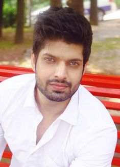 a man sitting on top of a red bench next to a park filled with trees