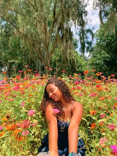 a woman sitting in the middle of a field of flowers