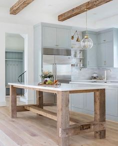 a kitchen with an island and wooden beams in the ceiling, along with stainless steel appliances