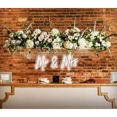 a sign that says mr and mrs hanging from the side of a brick wall with flowers on it