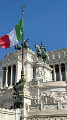 the italian flag is flying in front of an ornate building with statues on it's sides