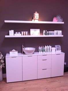 a bathroom with white cabinets and shelves filled with personal care items on top of them