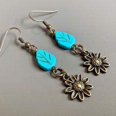 "Sunflower Earrings - Brass plated Sunflowers dangle from Turquoise Czech Glass Leaf Beads and Twisted Antiqued Brass plated Rings. Antiqued Brass Earwires Earrings measure j2.25\" from top of earwire to bottom of flowers." Turquoise Dangle Earrings With Flower Charm, Nature-inspired Dangle Earrings With Flower Charm, Turquoise Flower-shaped Earrings With Flower Charm, Adjustable Flower-shaped Nature-inspired Earrings, Turquoise Earrings With Flower Charm, Nature-inspired Drop Earrings With Flower Charm, Nature-inspired Flower Charm Drop Earrings, Nature-inspired Drop Flower Earrings With Charm, Vintage Dangle Earrings With Flower Charm