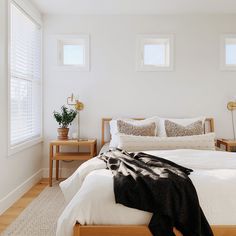 a bed with white linens and pillows in a bedroom next to two nightstands