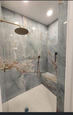 a bathroom with marble walls and flooring, shower head and hand held faucet