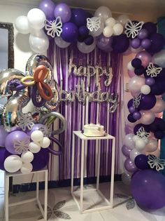 balloons and streamers are set up in front of a purple backdrop with the words happy birthday on it