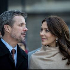 a man and woman standing next to each other in front of a crowd on the street