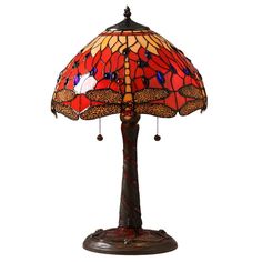 a lamp that is sitting on top of a wooden stand with a red and yellow dragonfly