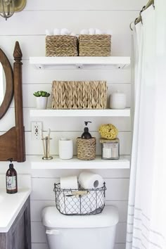 a white toilet sitting in a bathroom next to a wooden shelf filled with baskets and towels