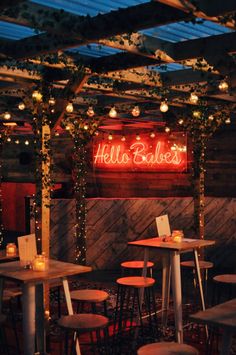 the inside of a restaurant with wooden tables and stools, lit up by lights