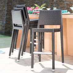 three chairs sitting on top of a patio next to a table with flowers in the background