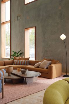 a living room filled with lots of furniture next to large windows on top of a wall