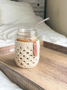 a mason jar with a straw in it sitting on a wooden tray next to a bed