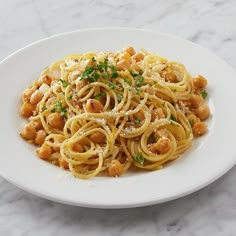 pasta with chickpeas and parmesan cheese in a white bowl on a marble table