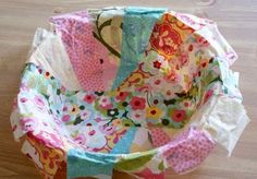 a colorful flowered fabric bowl sitting on top of a wooden table