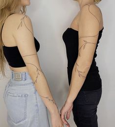 two women with tattoos on their arms standing next to each other