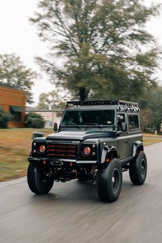 a black jeep driving down a street next to trees