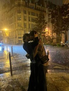 two people standing in the rain hugging each other