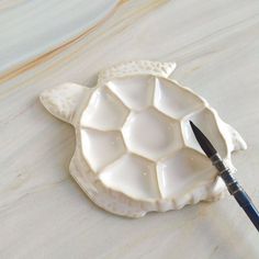 a turtle shaped dish with a paintbrush in it