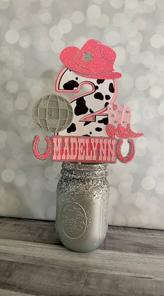 a mason jar with some paper cutouts on it and a cow in a hat