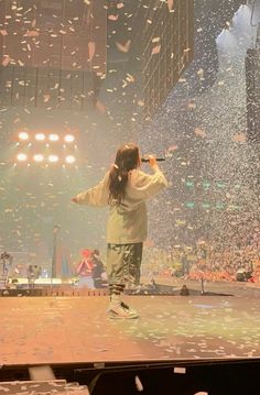 a person standing on a stage with confetti falling from the ceiling behind them