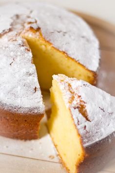 a close up of a cake with powdered sugar on it and one slice cut out