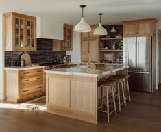 a large kitchen with wooden cabinets and white counter tops, along with bar stools