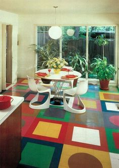 a kitchen with colorful flooring and potted plants on the table in front of an open window