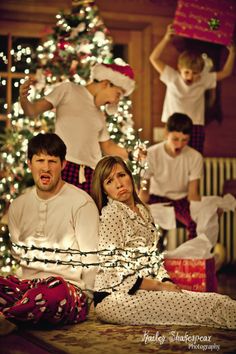 a family sitting on the floor in front of a christmas tree with lights around them