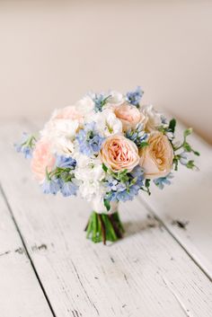 a bouquet of flowers sitting on top of a white wooden table next to a wall