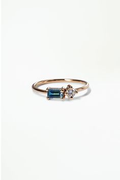 a gold ring with two blue stones on the front and one green stone on the back