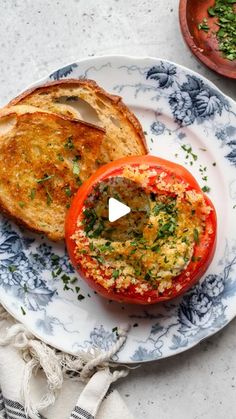 an open faced sandwich on a blue and white plate next to a bowl of herbs