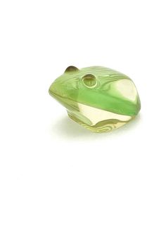 a green glass frog sitting on top of a white surface