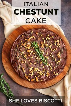 a chocolate cake with sprinkles and rosemary on a wooden platter next to a napkin