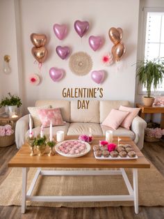 a valentine's day coffee table with pink and gold balloons on the wall above it