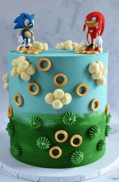 a sonic the hedgehog themed cake with two figures on top and gold rings around the edges