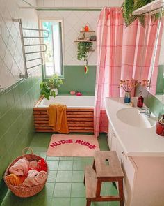 a bathroom with green tile and pink curtains