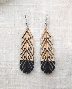 two tone wooden earrings with black and gold details on white linen background, close up