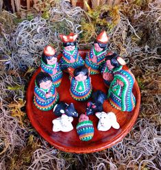 several small figurines are placed on a wooden tray with grass in the background