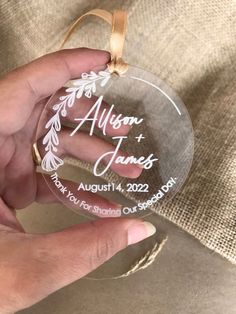 a person holding a glass ornament that says, personalized with the names and date