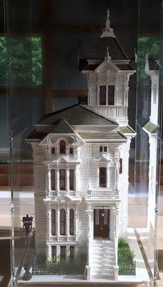 a model of a white house in a glass case on a table next to a window