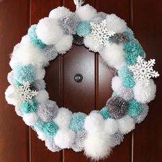 a snowflake and pom - pom wreath on a door