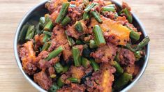 a metal bowl filled with green beans and meat