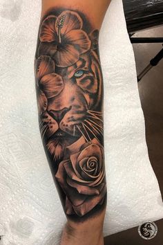 a tiger with flowers on his arm is shown in black and grey ink, while the other half has blue eyes