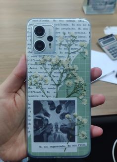 a person holding up a cell phone case with pictures and flowers on it in front of a table