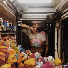 a man standing in the back of a truck filled with lots of stuffed animals and toys